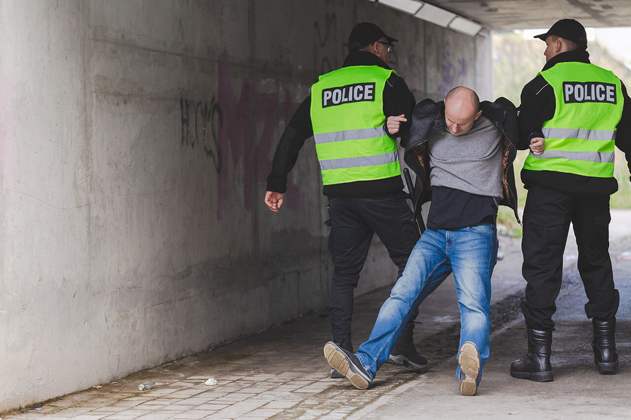 Man being apprehended by police officers in Melbourne, symbolising the start of a criminal law case.