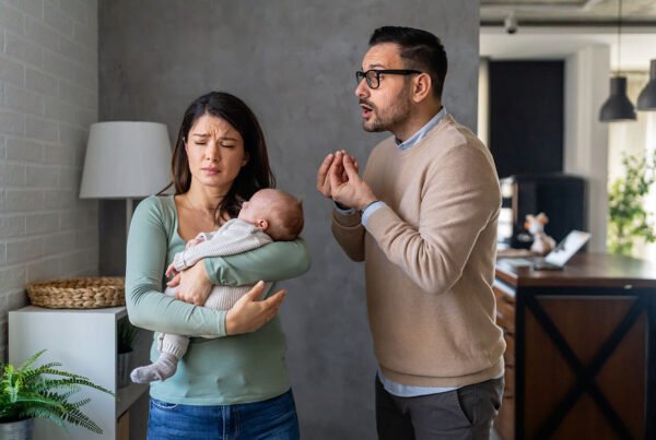 A distressed mother holding a baby while having an argument with a concerned father.