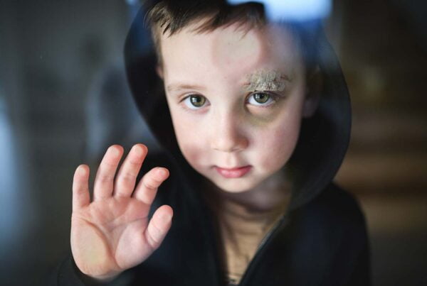 Child behind glass reaching out, need for child protective services.