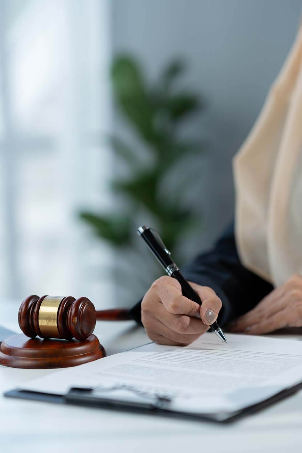 Lawyer signing urgent legal documents with a gavel in the background, symbolising injunctions and urgent applications.