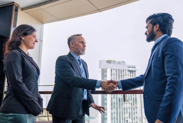 Shareholder dispute resolution meeting in Melbourne CBD – two business professionals shaking hands as a solicitor observes, discussing shareholder disputes FAQs.